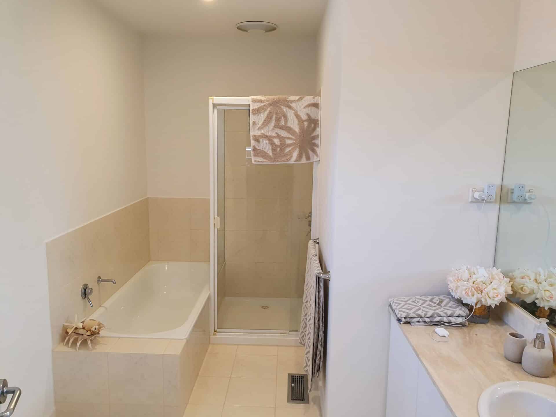 A white bathroom with a bathtub, glass shower and a sink.