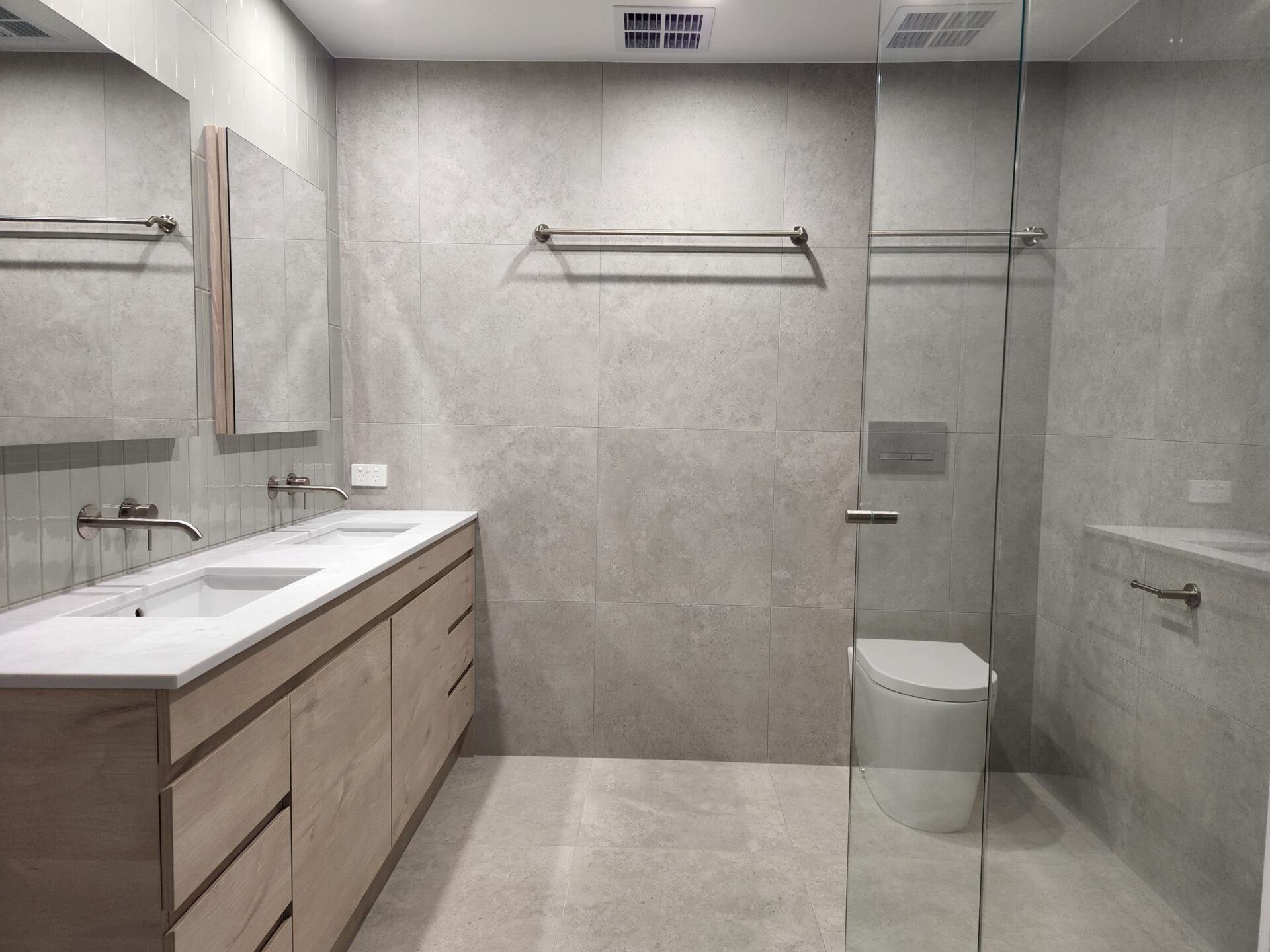 A bathroom with a modern vanity, toilet, and shower.